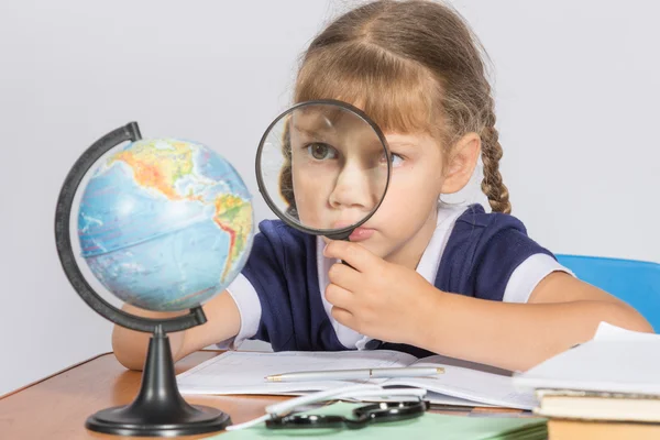Studentessa guardando globo attraverso una lente d'ingrandimento — Foto Stock