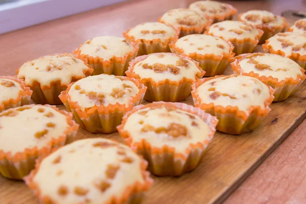 Frisch gebackene Muffins liegen auf einem Holzblech — Stockfoto