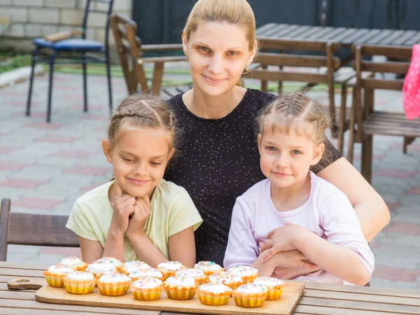 Maman et deux filles assises à une table sur laquelle gisaient les cupcakes de Pâques cuits — Photo