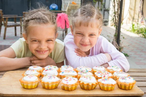 Две девушки притворяются смешными, сидят перед пасхальными кексами — стоковое фото