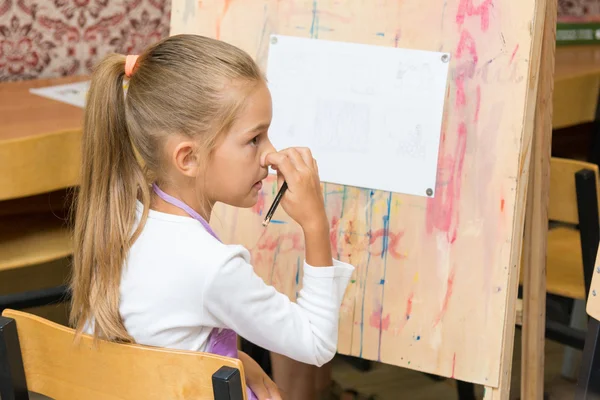 Mädchen, das sich die Nase kratzt, hört dem Lehrer beim Zeichenunterricht aufmerksam zu — Stockfoto