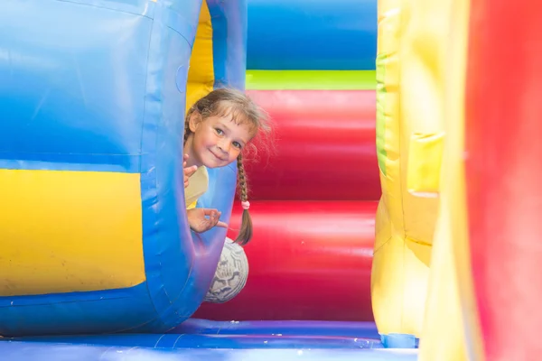 Happy little girl got out of the inflatable soft barrel while playing on the trampoline — Stock Photo, Image