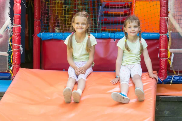 Twee meisjes naprygalis zachte kinderspeelkamer en zat naar beneden om uit te rusten — Stockfoto