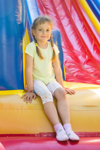 Vijfjarig meisje zittend op een grote opblaasbare trampoline — Stockfoto
