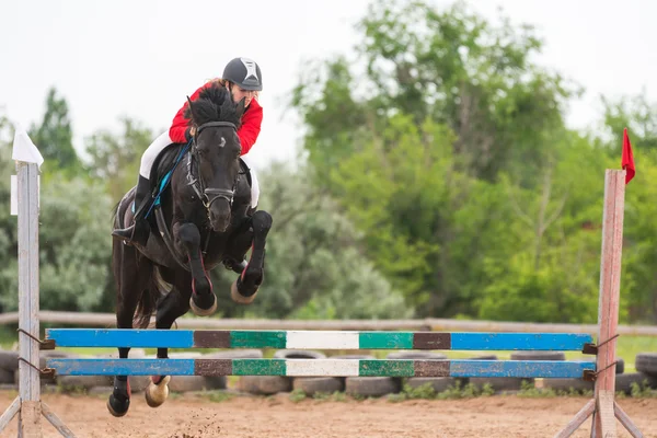 Wolgograd, Rusland-19 juni 2016: de atleet voert een sprong op een paard door de barrière — Stockfoto
