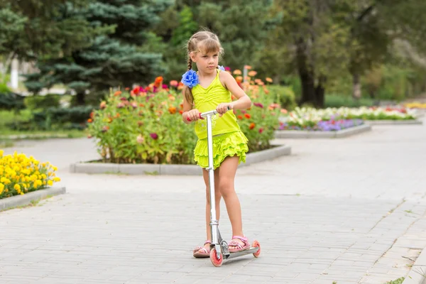 Girl riding a scooter down the avenue — Stock Photo, Image