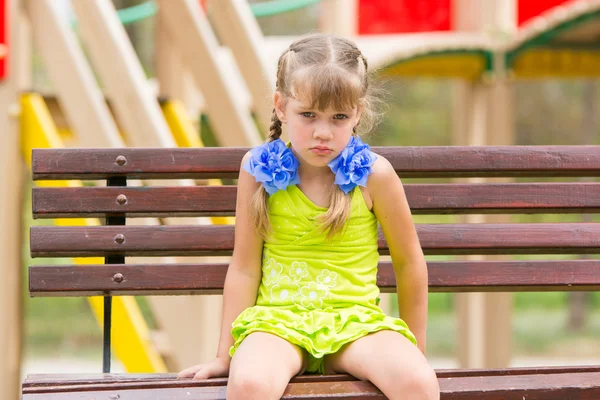 Obrażony pięć lat dziewczyna siedzi na ławce na placu zabaw — Zdjęcie stockowe