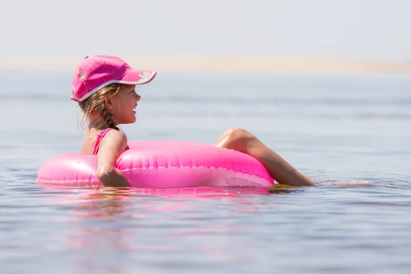 Девушка в кепке плавала в реке, сидя на круге плавания — стоковое фото