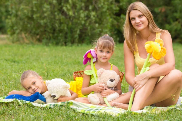 Moeder en dochter zitten met zacht speelgoed op een picknick en kijken naar het schot — Stockfoto