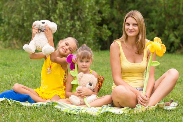 Mother and daughter sitting with soft toys on a picnic — Stock Photo, Image