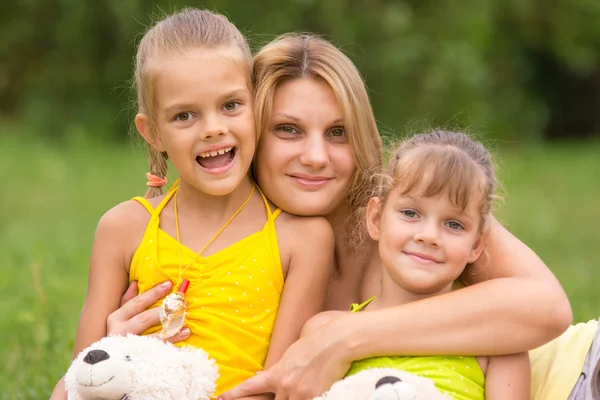 Giovane madre che abbraccia le sue due figlie, cinque e sette anni — Foto Stock