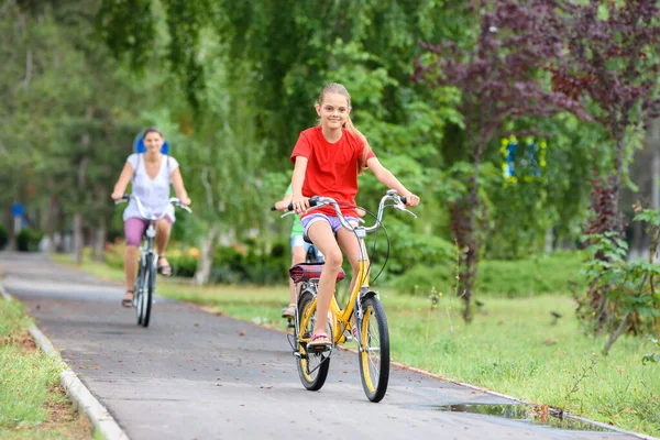 女の子とお母さんは路地に沿って自転車に乗る — ストック写真