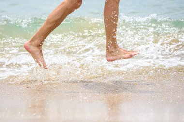 Sahilde koşan komik ayaklar Deniz suyu sıçratıyor