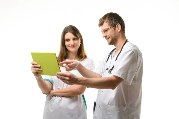 タブレットのコンピューター画面を見ながら患者のテストを議論する2人の医師 — ストック写真