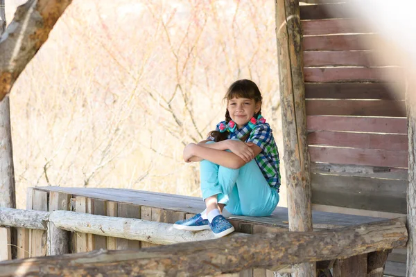 10歳の女の子が木製の展望台に座って フレームに陽気に見える — ストック写真