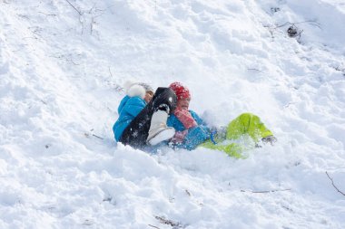 İki kız kar yığınına doğru kayıyor.