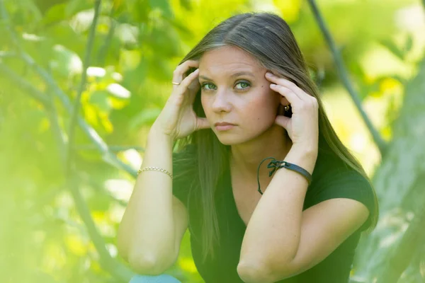 Een Verdrietig Meisje Zit Een Achtergrond Van Gebladerte Houdt Haar — Stockfoto