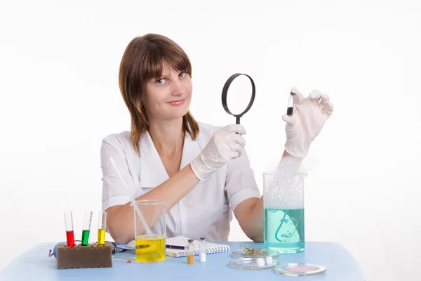 Pharmacist considers powder through a magnifying glass — Stock Photo, Image
