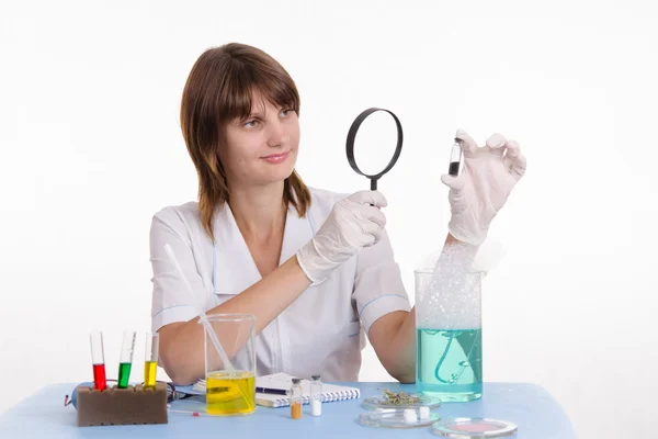 Cientista examina a medicina através de uma lupa — Fotografia de Stock