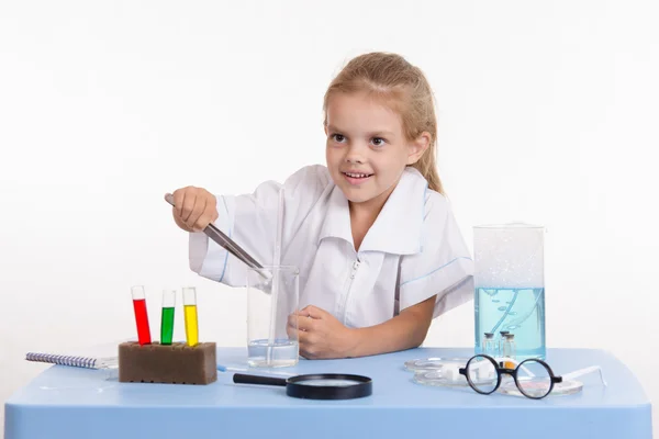 Дівчинка кидає шматок реагенту в колбу в класі хімії — стокове фото