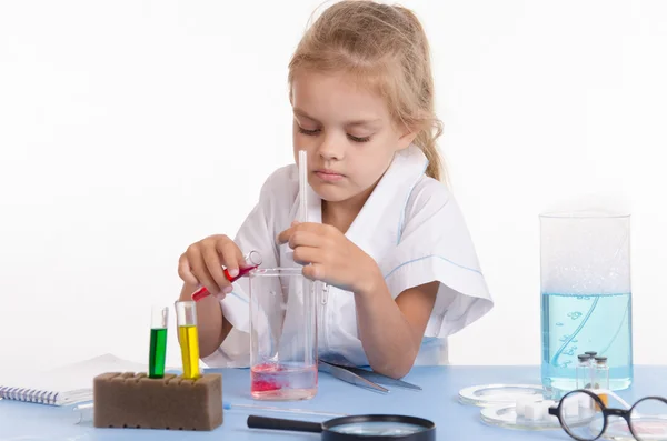 Schoolgirl pouring red liquid a flask in chemistry class — Stock Photo, Image