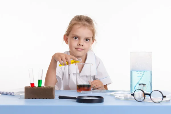 Gekke scheikundige giet gele vloeistof in een maatkolf — Stockfoto