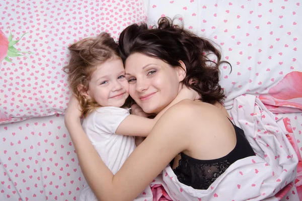 Mum embraces daughter lying in bed — Stock Photo, Image