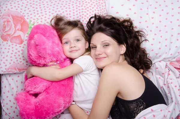 Mom 抱擁彼女の娘がベッドで横になっています。 — Stock fotografie