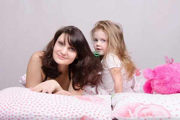 Maman et fille avec une brosse à cheveux dans son lit — Photo