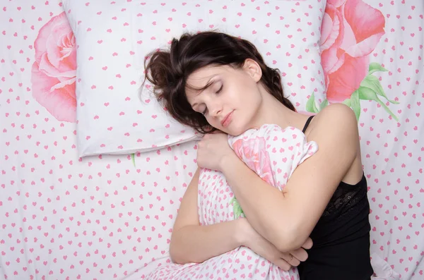 Vrouw knuffelen hoofdkussen in bed — Stockfoto