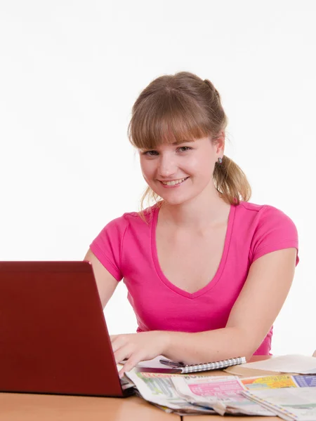 Flicka med laptop och tidningen sitter vid bord — Stockfoto