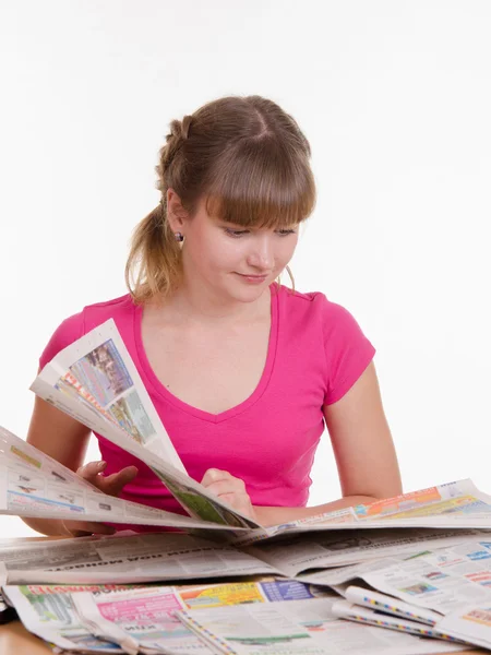 Girl thumbs through the newspaper to find right ads — Stock Photo, Image