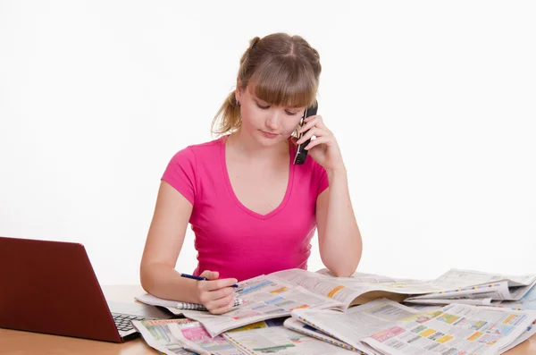 Young woman calling on a newspaper ad — Stock Photo, Image