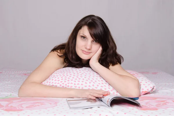 Menina bonita lendo uma revista maravilhada na cama — Fotografia de Stock