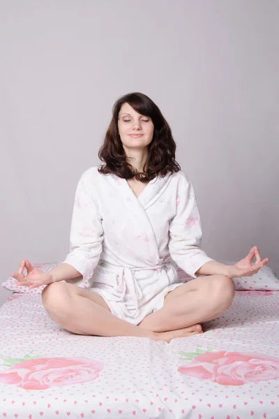 Kvinna som mediterar sitter på sängen — Stockfoto