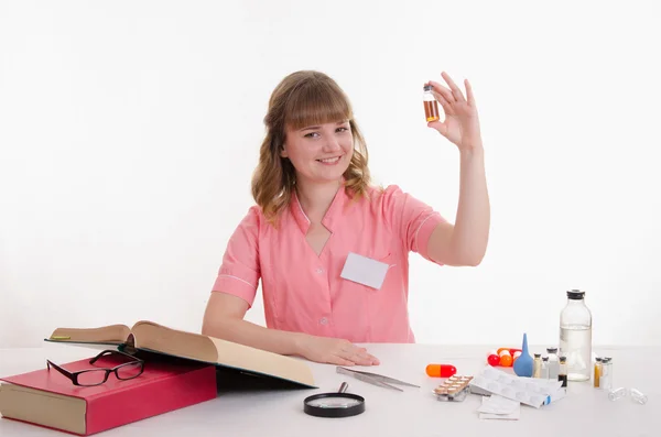 Apotekare sitter vid ett bord med en ampull — Stockfoto