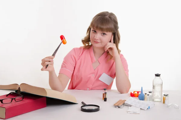 Medical student sitting at a table with tweezers on the pill — Stock Photo, Image