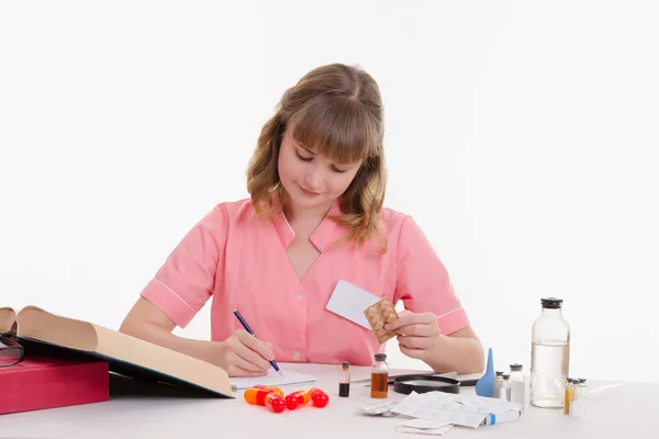 Pharmacist rewrites name tablets to notebook — Stock Photo, Image