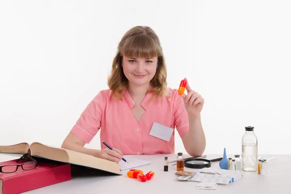 Pharmacist writing in a notebook composition pills — Stock Photo, Image