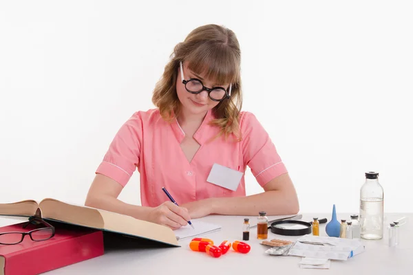 Pharmacist reading guide writes notes in a notebook — Stock Photo, Image