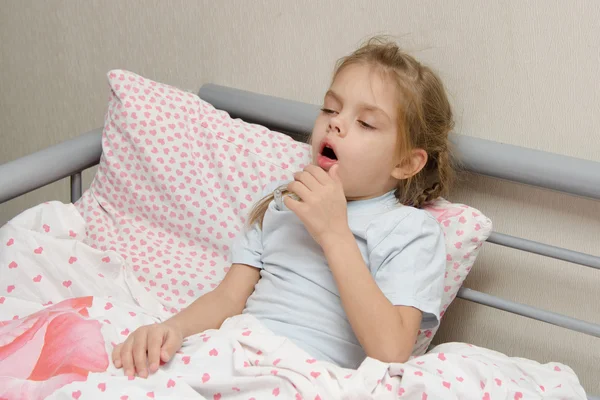 ベッドの咳で横になっている病気の女の子 ストック写真
