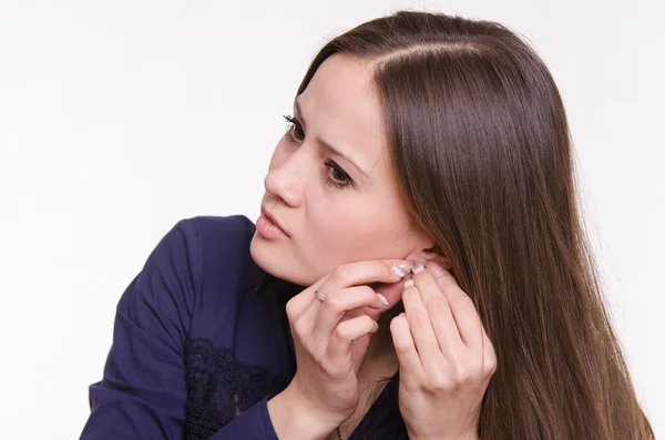 Portrait of a pretty girl corrects an earring in his ear — Stock Photo, Image