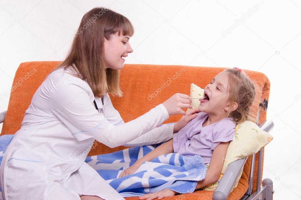 The doctor examines the throat Sick little girl in bed