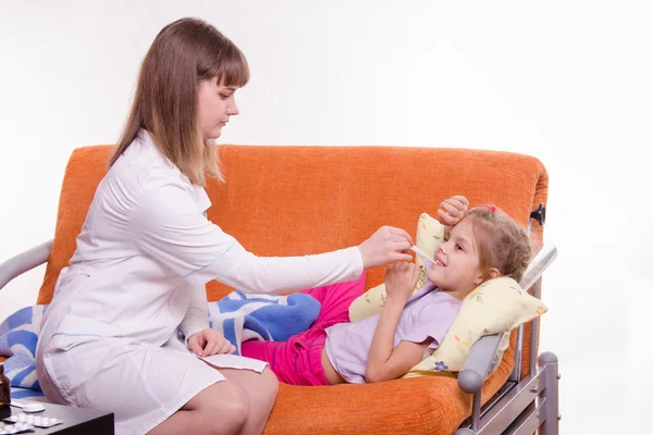 Doctor measures temperature the sick girl at home — Stock Photo, Image