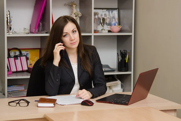 Employee of the office sitting a table holding phone and looking at frame — Stock Photo, Image