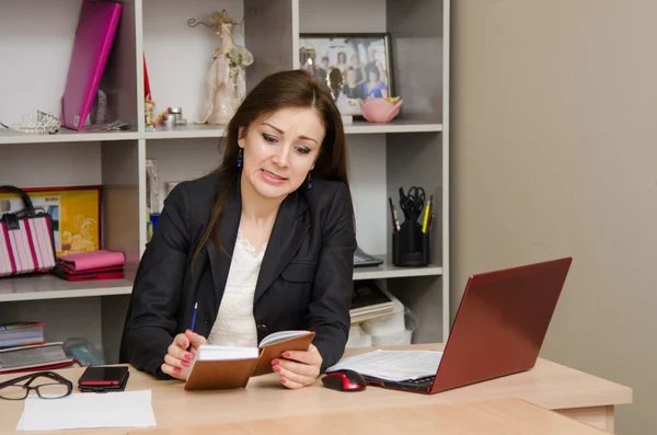 Tjejen på kontoret ser ilsket till anteckningsboken — Stockfoto