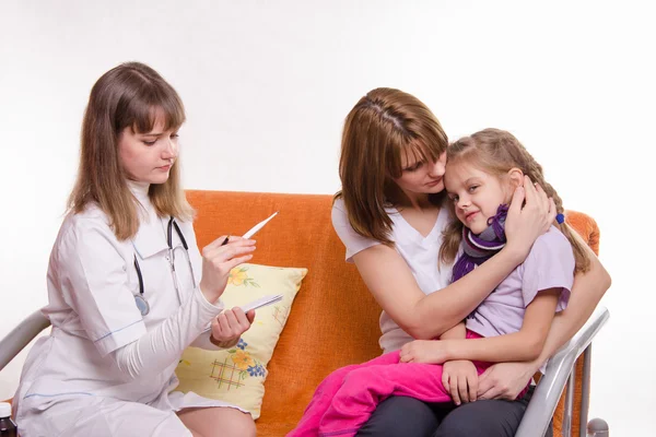 Doctor looks temperature on a thermometer sick girl and her mother comforts — Stock Photo, Image