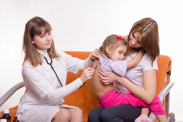 Kinderarzt hört atmendem Mädchen zu, das in Händen der Mutter sitzt — Stockfoto