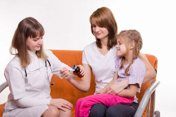 Pediatrician pours medicine into a spoon, which holds mother of sick child — Stock Photo, Image