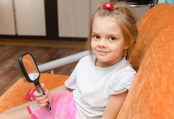 Little girl with a mirror sits on the couch — Stock Photo, Image